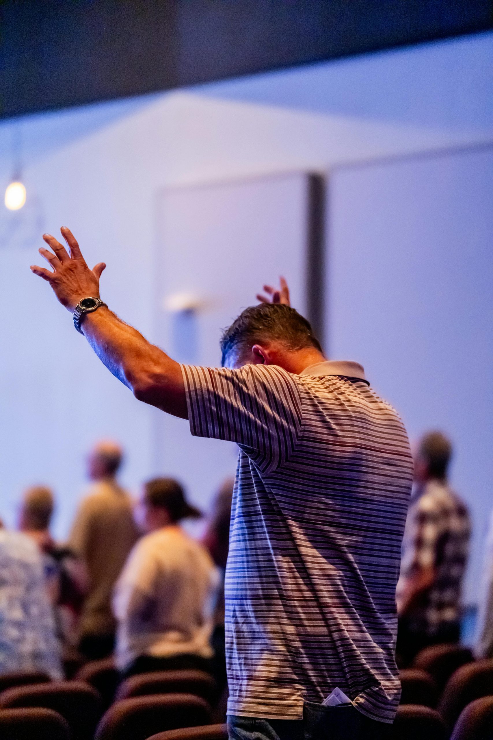 A man raises his arms during a vibrant church service, expressing worship.